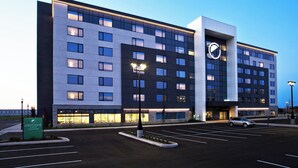A modern hotel with a large parking lot and a prominent clock tower.