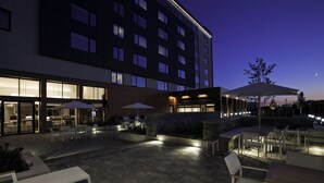 An outdoor patio area with seating and tables, illuminated by ambient lighting.