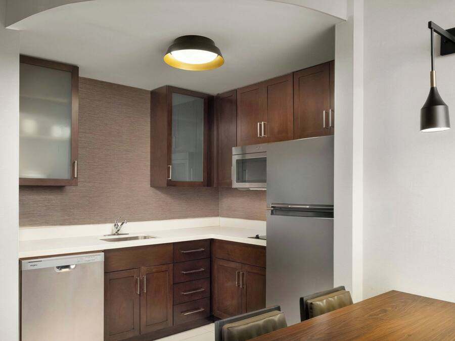 A modern kitchen with wooden cabinets, stainless steel appliances, and a built-in dishwasher.