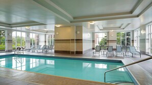 An indoor swimming pool with clear water, surrounded by lounge chairs and tables, large windows, and a tiled floor. - Residence Inn by Marriott Ottawa Airport (Ottawa)