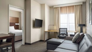 A hotel room with a bed, a desk with a chair, a sofa, a TV, and a window with curtains. - Residence Inn by Marriott Ottawa Airport (Ottawa)