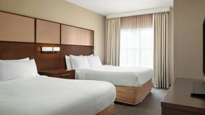 A hotel room with two beds, a wooden headboard, a nightstand, a TV, and a window with curtains. - Residence Inn by Marriott Ottawa Airport (Ottawa)