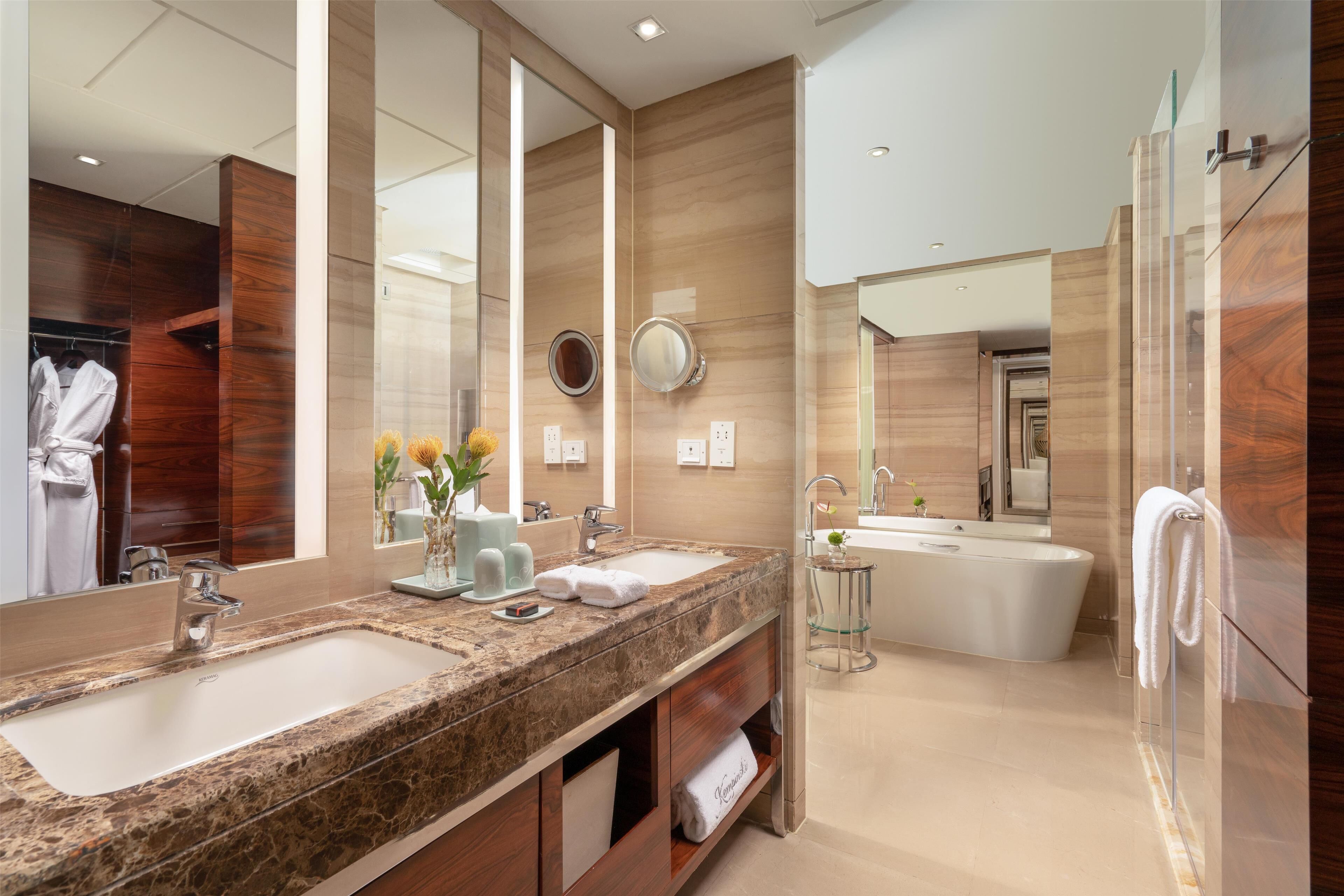 Un baño moderno con dos lavamanos, un espejo grande y una bañera independiente.