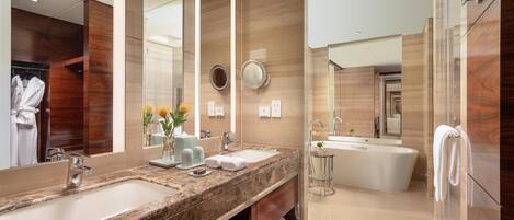 Un baño moderno con dos lavamanos, un espejo grande y una bañera independiente.