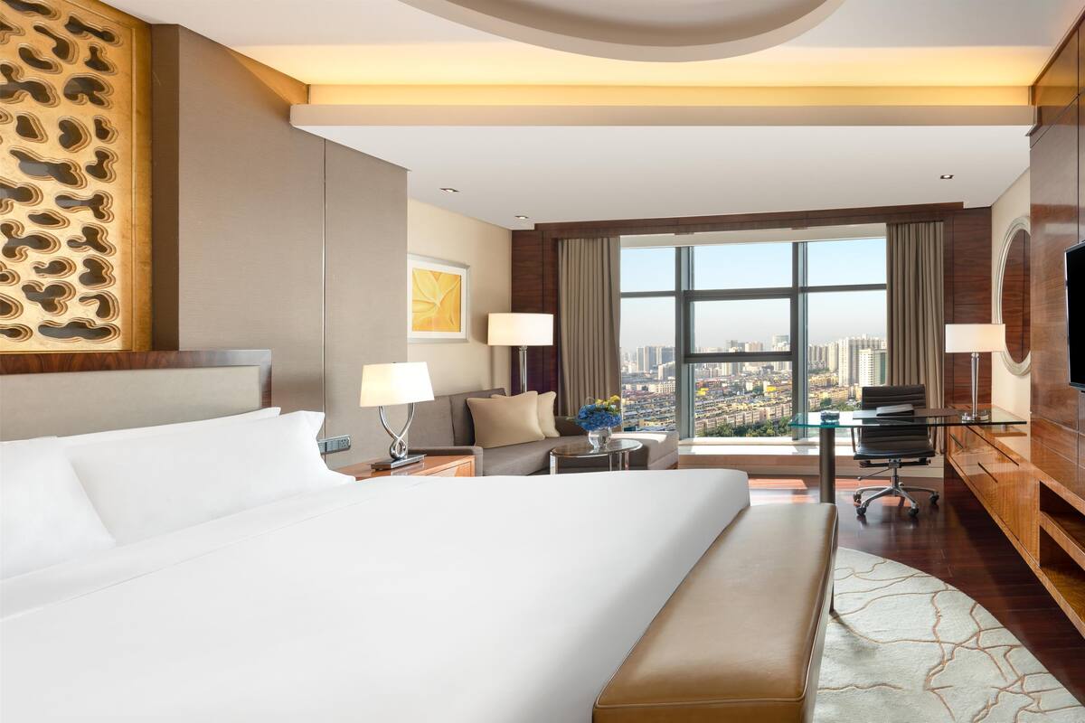 Une chambre d’hôtel avec un grand lit, un bureau, une chaise et une vue sur la ville.