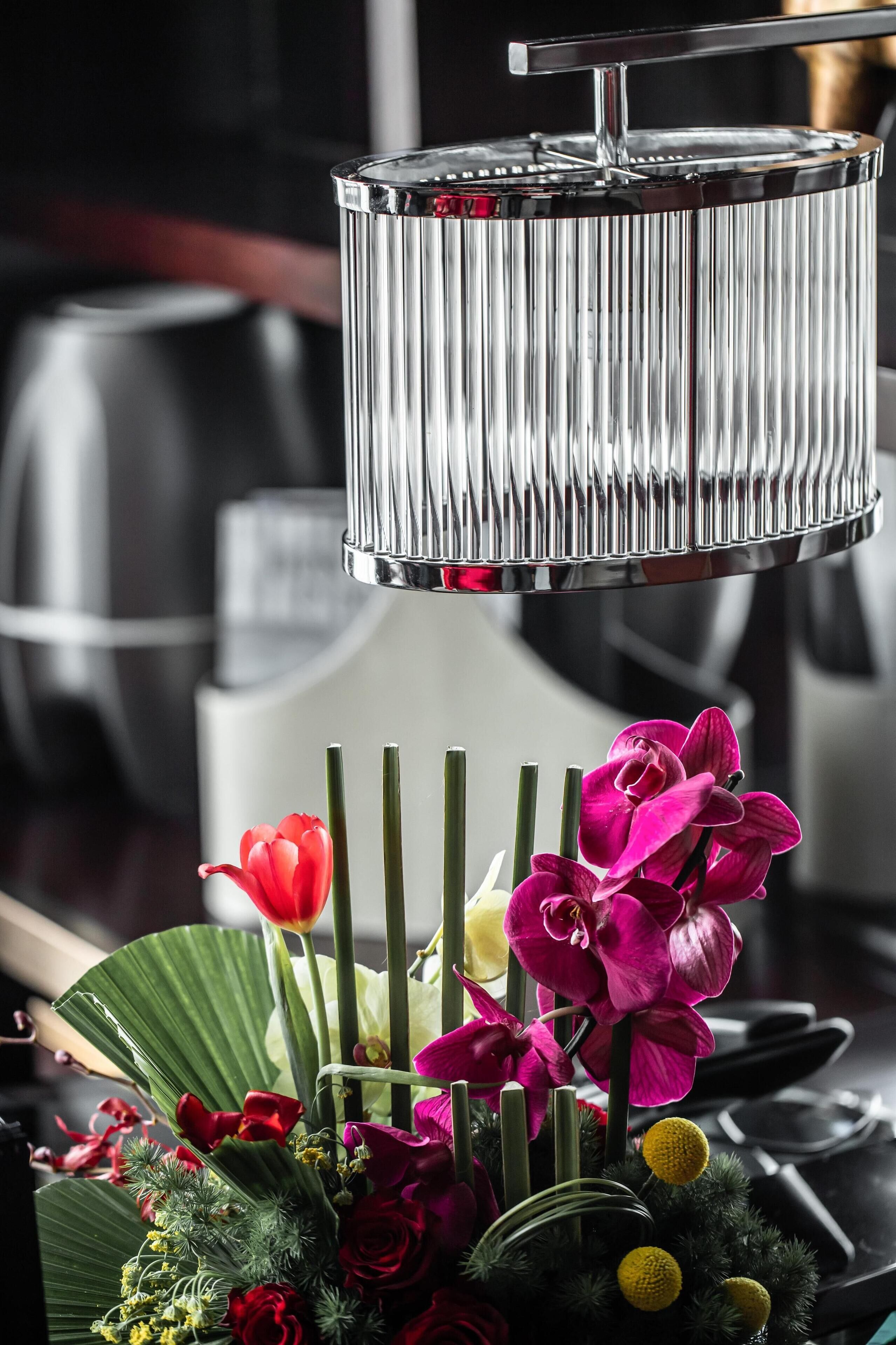 A kitchen with a stainless steel appliance, a hanging light fixture, and a floral arrangement on the counter.