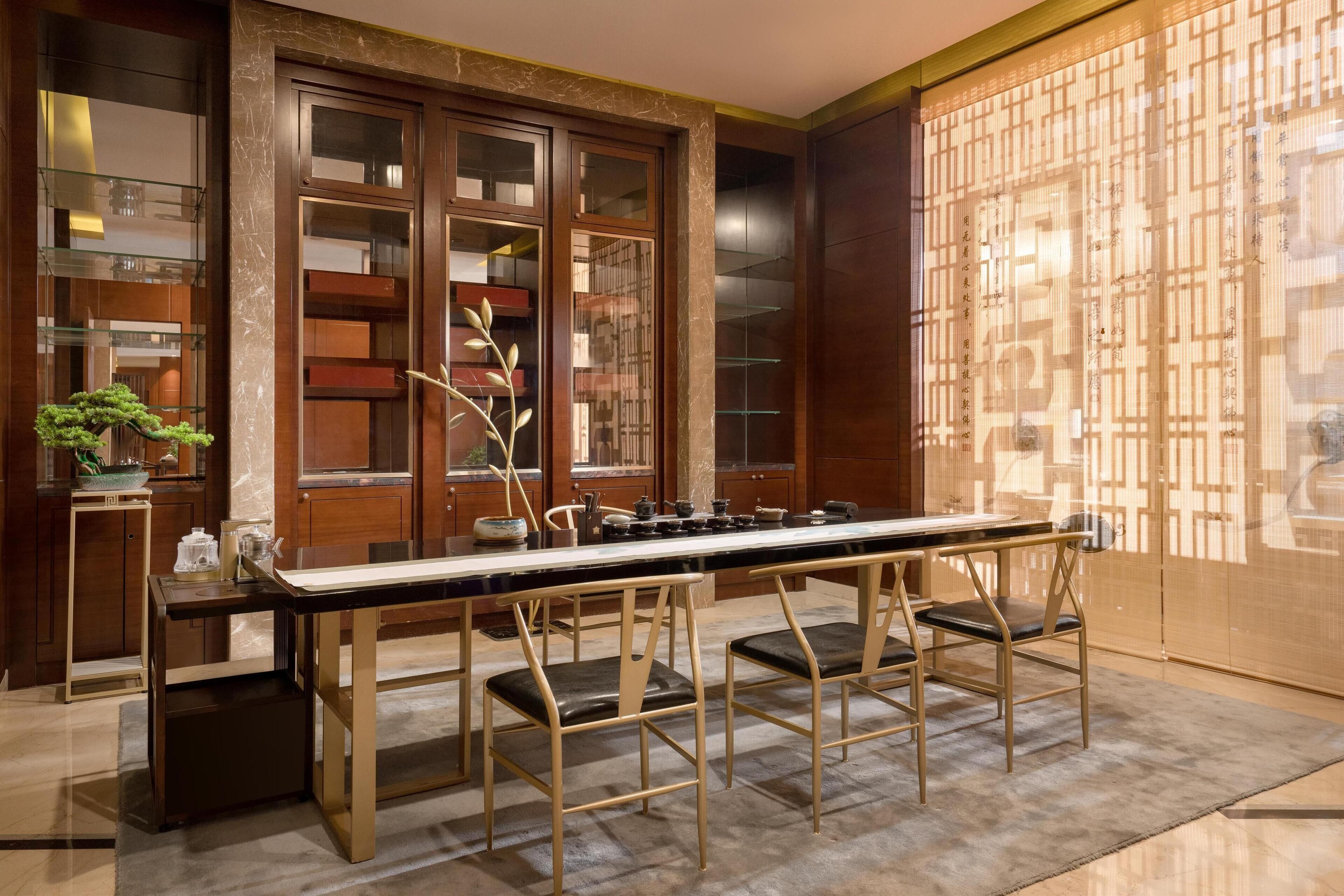 A modern kitchen with a long dining table, wooden cabinets, and a decorative screen.