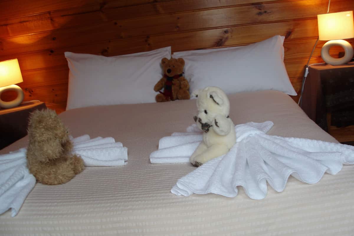 Un lit bien fait, avec des serviettes blanches et un ours en peluche.