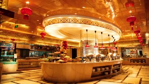 Um amplo saguão de hotel com área de bar circular central, diversas opções de assento e design de teto moderno.