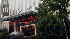 Um hotel com fachada de vidro moderna e uma placa vermelha destacada.