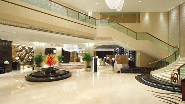 Um amplo hall com uma área circular central, escada e balcão de recepção.