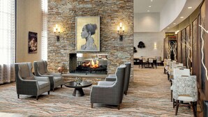 A lobby with a stone wall, a fireplace, and seating areas. - Embassy Suites Chattanooga / Hamilton Place (Chattanooga)