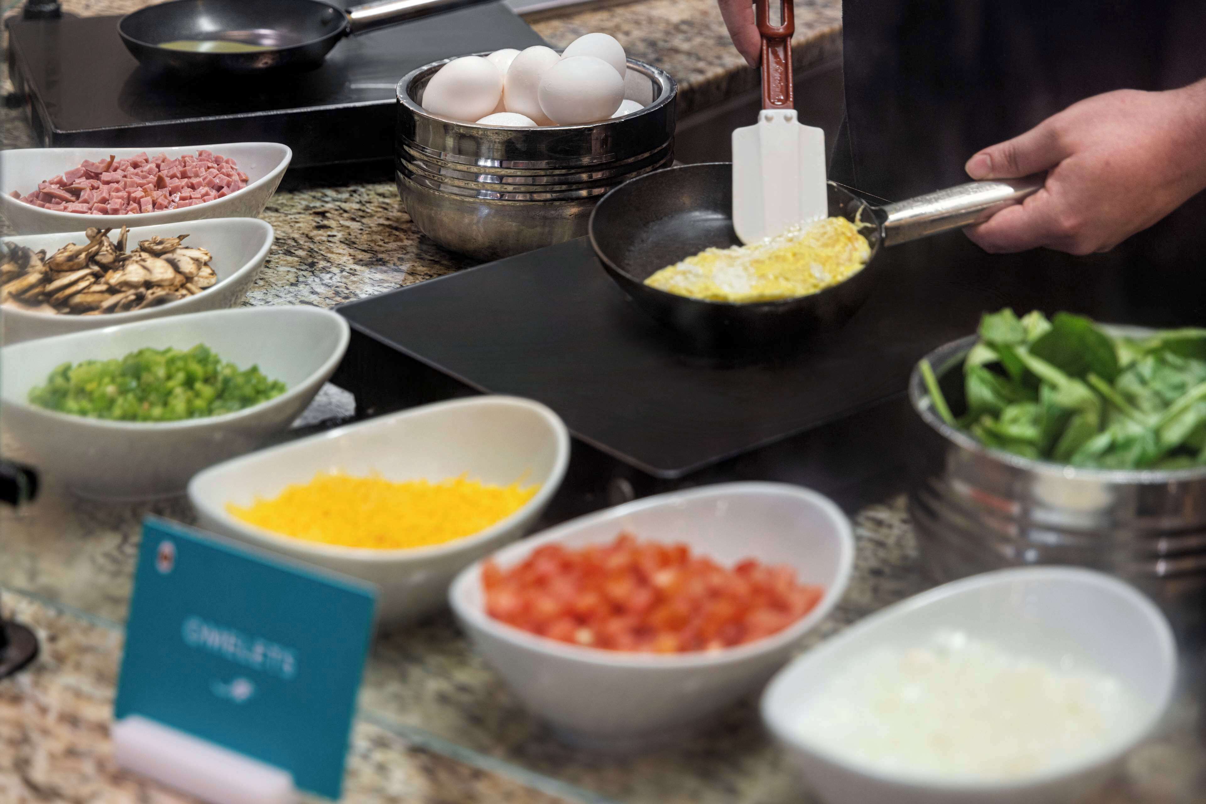 A kitchen counter with various food ingredients and a person grating cheese.