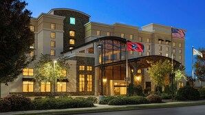 A hotel with a modern design, featuring a curved entrance canopy and a flag. - Embassy Suites Chattanooga / Hamilton Place (Chattanooga)