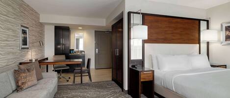 A hotel room with a bed, a desk, a sofa, and a large mirror.