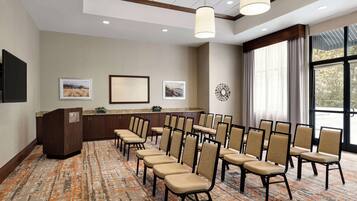 A conference room with a long table, chairs, a podium, and framed pictures on the wall.