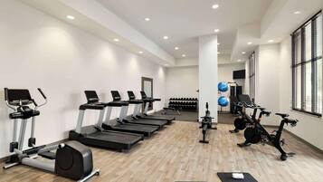 Un gimnasio con cintas de correr, elípticas y bicicletas estáticas.
