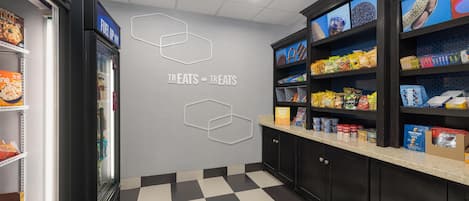 Un bar de aperitivos con suelo a cuadros, estantes llenos de productos y una pared con formas hexagonales.