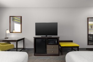 A hotel room with a flat-screen TV, a minibar, a desk with a lamp, two beds, and a mirror. - Hampton Inn Cotulla (Cotulla)