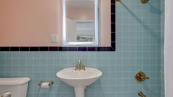 Een badkamer met een wit wastafel, toilet en douche.