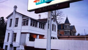 Een bord voor 'Gold Springs Hot Springs' met een Victoriaans gebouw op de achtergrond.