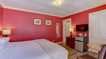 A room with a bed, a desk, a chair, a TV, and a refrigerator.