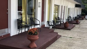 Een hotelentree met verschillende terrasjes, elk met een bloempot en stoelen.