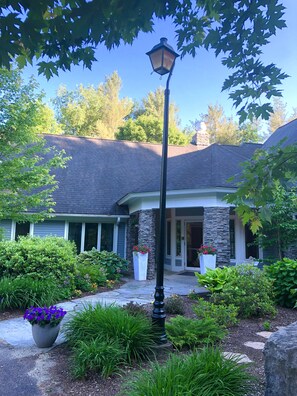 A house with a stone facade, a front porch, and a well-maintained garden with various plants and flowers.