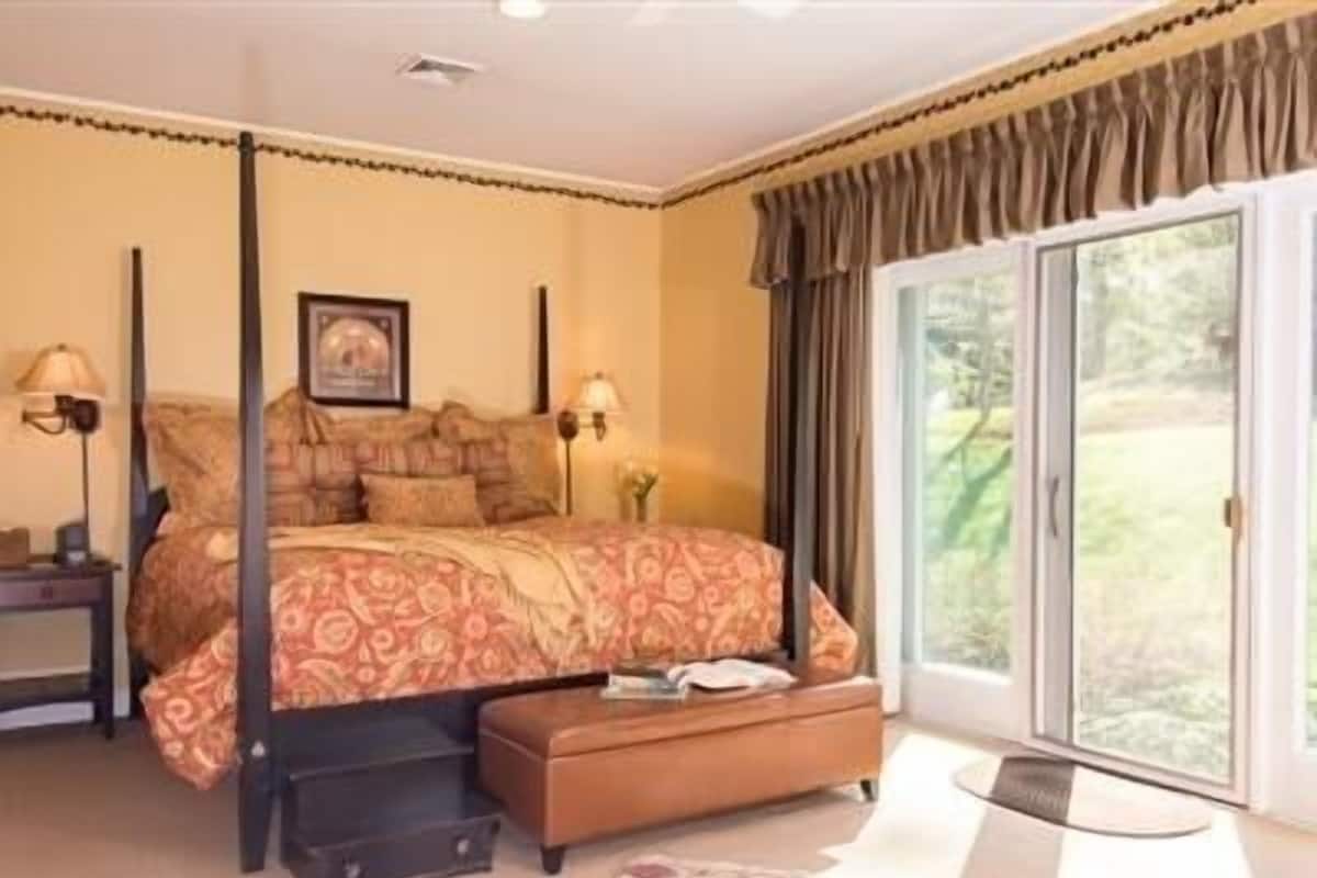 Un dormitorio con cama, mesita de noche, lámpara, cómoda y una puerta corrediza de vidrio que da a un balcón.