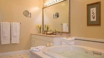 A bathroom with a bathtub, a vanity with a mirror, and two towels hanging on the wall.