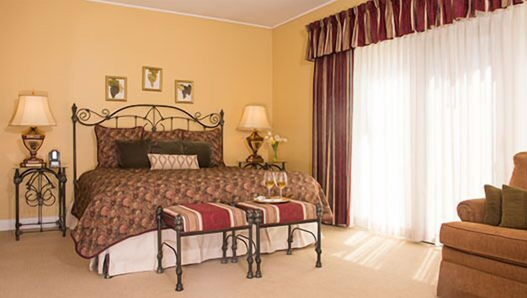 A neatly arranged bedroom with a bed, bedside tables, a bench, and a chair.