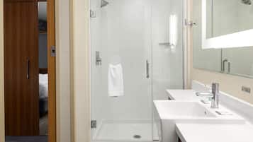 A modern bathroom with a glass-enclosed shower, two sinks, and a large mirror.