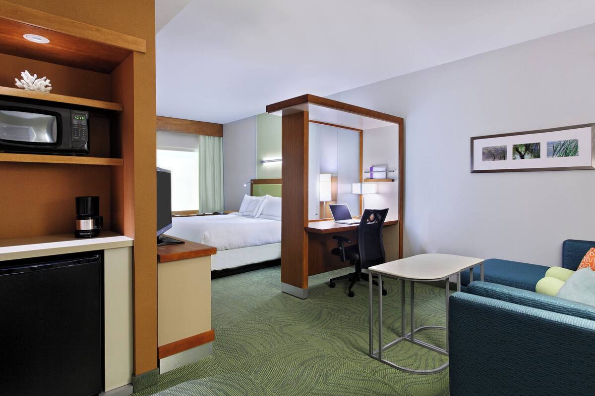 A hotel room with a bed, desk, chair, and a small table.