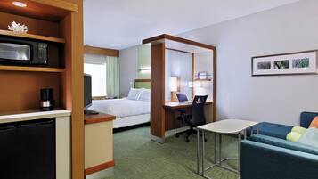 Una habitación de hotel con cama, escritorio, silla y una mesita.