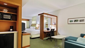 A hotel room with a bed, desk, chair, kitchenette, and a small seating area. - SpringHill Suites Pensacola (Pensacola)