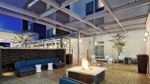 An outdoor patio area with a fire feature, seating, and a view of the building's interior. - SpringHill Suites Pensacola (Pensacola)