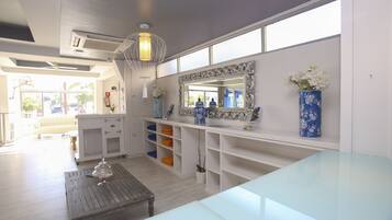 A modern hotel room with a large window, a white vanity with a mirror, and a blue vase with flowers.