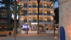 Un hotel con varios balcones, palmeras y una bandera.