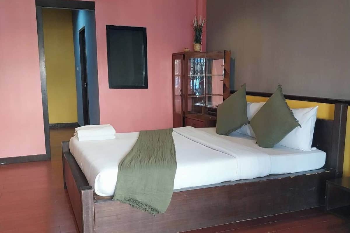 A bedroom with a wooden bed, a green throw blanket, and a nightstand with a lamp.
