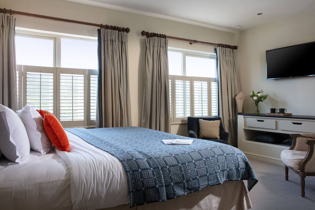 A hotel room with a bed, a desk, a chair, and a TV on the wall.