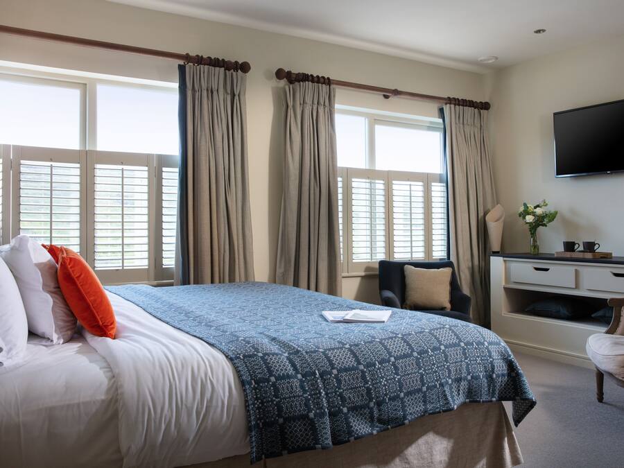 Ein Hotelzimmer mit Bett, Schreibtisch, Stuhl und Fernseher an der Wand.