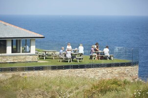 A coastal building with outdoor seating overlooking the sea.