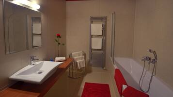 Un bagno moderno con lavandino, specchio, doccia e asciugamani rossi.