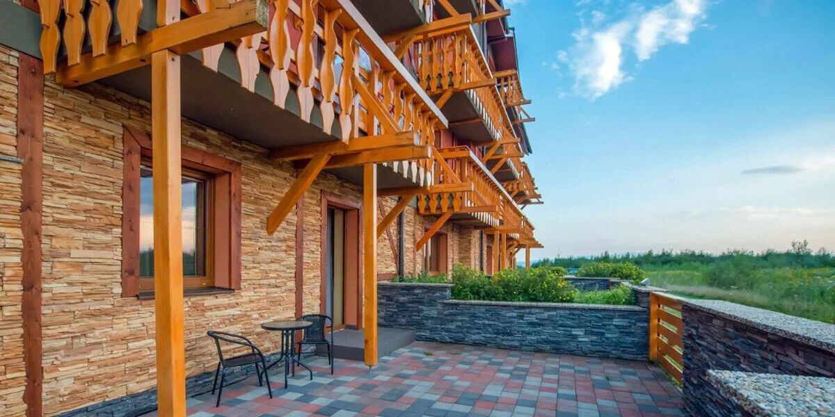 Un edificio con fachada de piedra, balcones de madera y un patio empedrado.