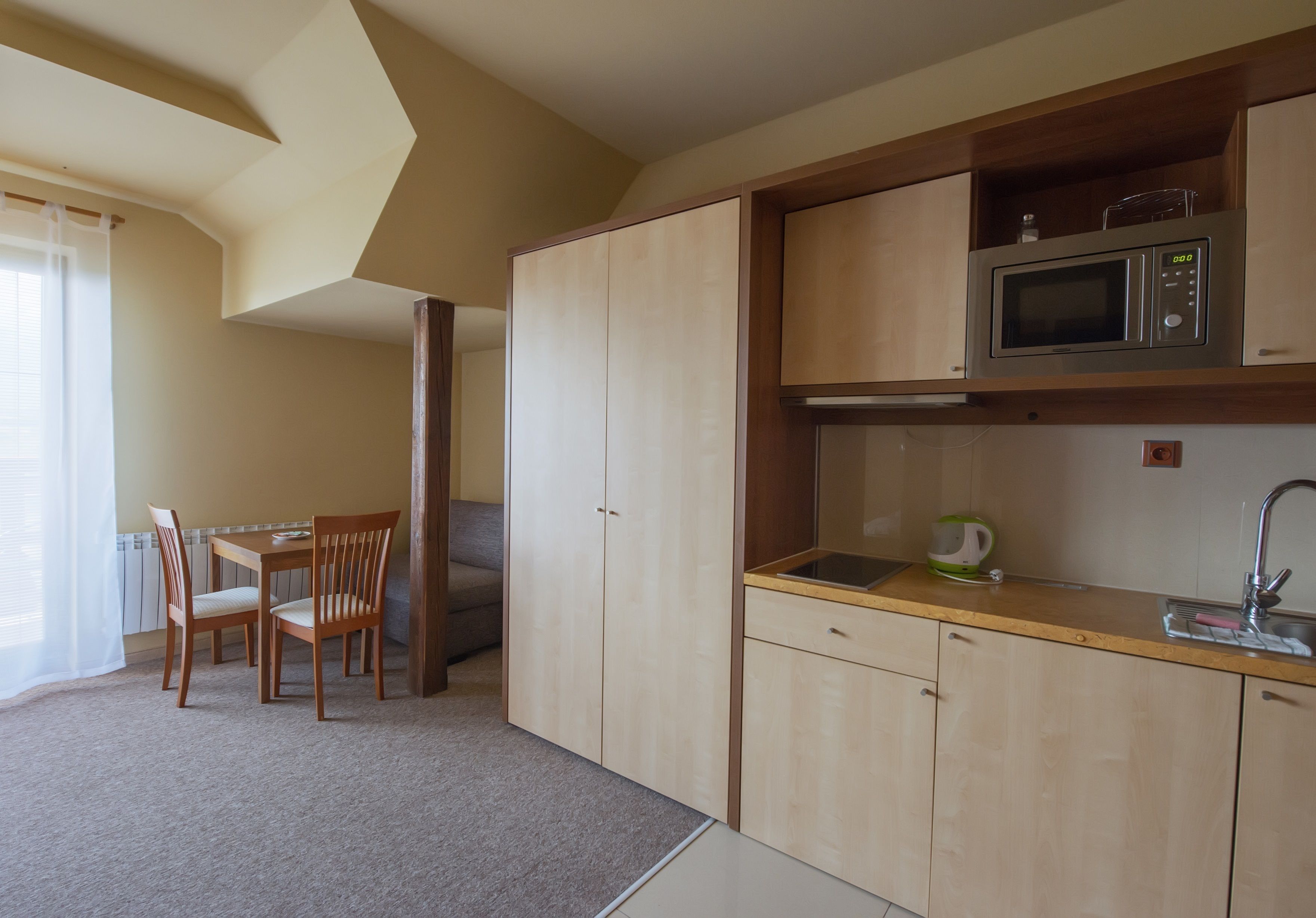 Una cocina compacta con armarios de madera, microondas y pileta. Cuenta con un comedor con mesa y sillas.