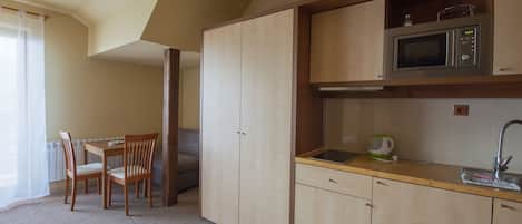 Una cocina compacta con armarios de madera, microondas y pileta. Cuenta con un comedor con mesa y sillas.