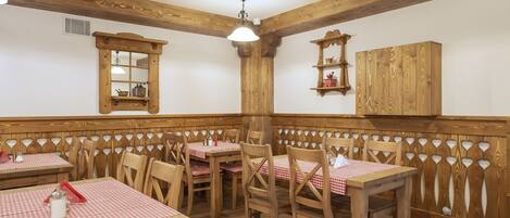 Een restaurant met houten meubels, geruit tafelkleed en een houten scheidingswand.