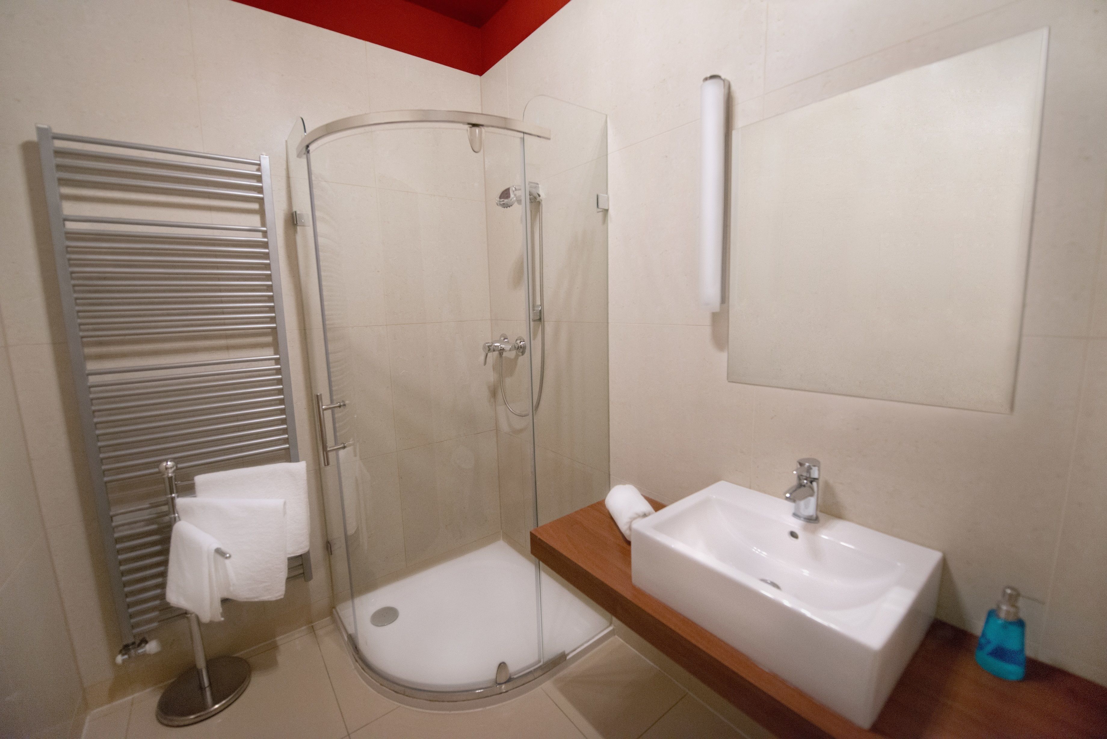 A modern bathroom with a glass shower enclosure, a built-in sink, and a towel rack.