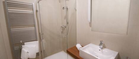A modern bathroom with a glass shower enclosure, a built-in sink, and a towel rack.