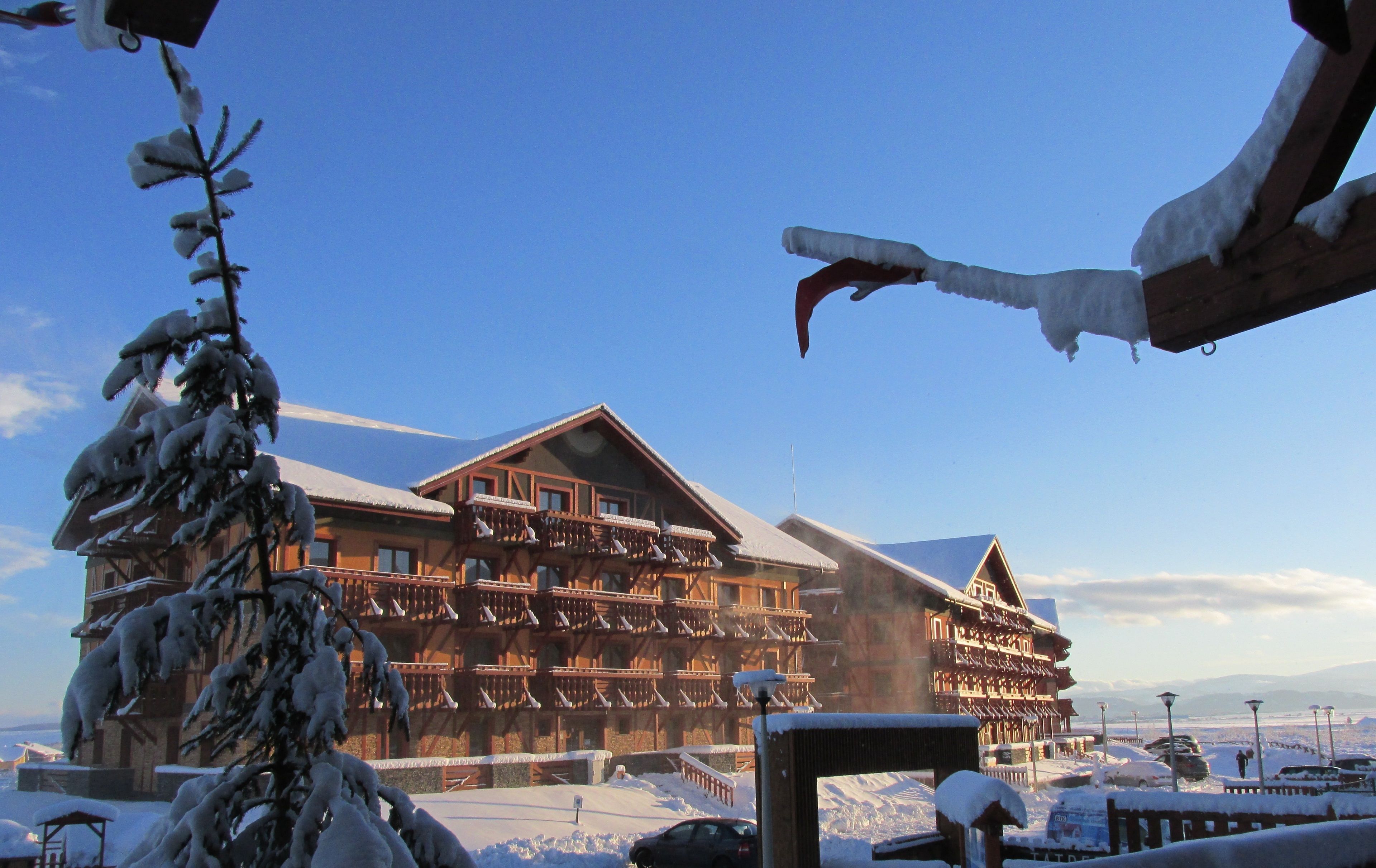 Un grand chalet en bois doté de nombreux balcons, surplombant un paysage enneigé.